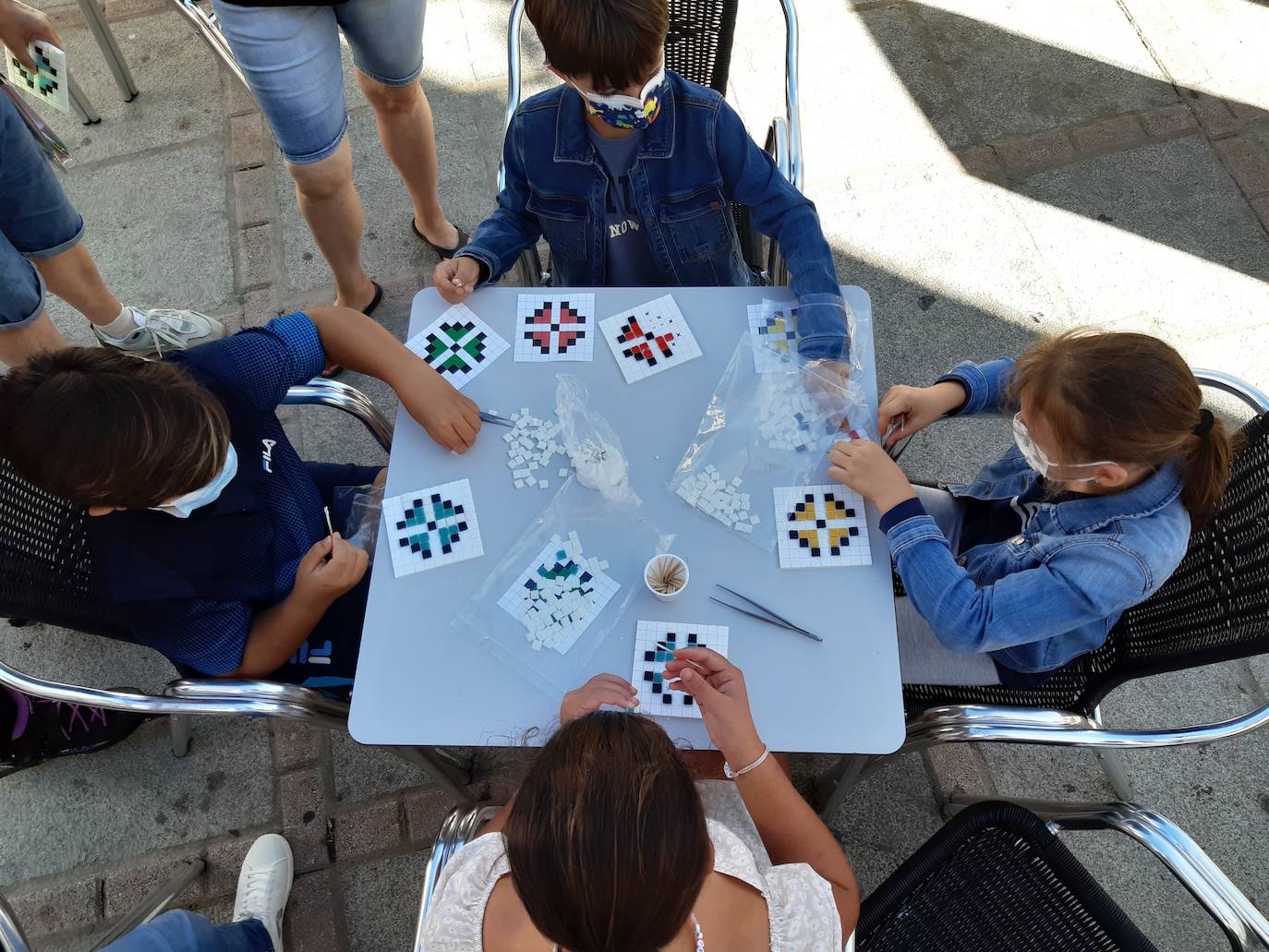 Varios niños realizan un pequeño mosaico con teselas de colores. 