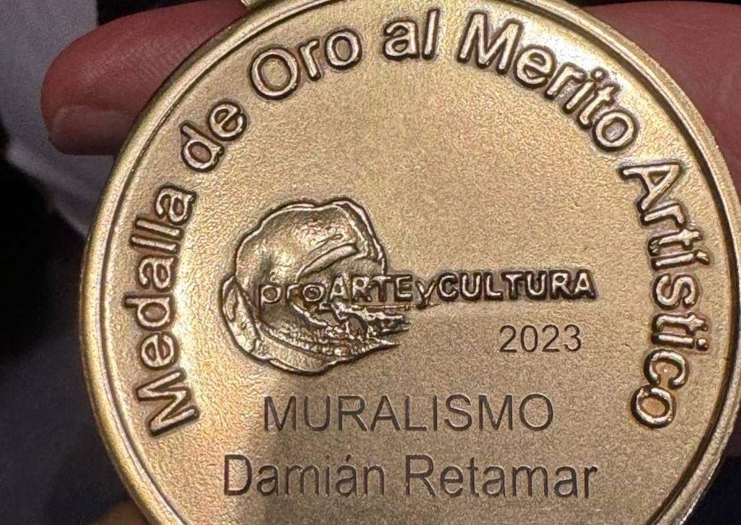 Leyenda y detalles del reverso de la Medalla de Oro Mayte Spínola 2023 a Damián Retamar.