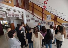 El delegado de Amical en Extremadura, José Hinojosa, explicando a los alumnos ante la exposición de republicanos en los campos nazis, en el recibidor del instituto.