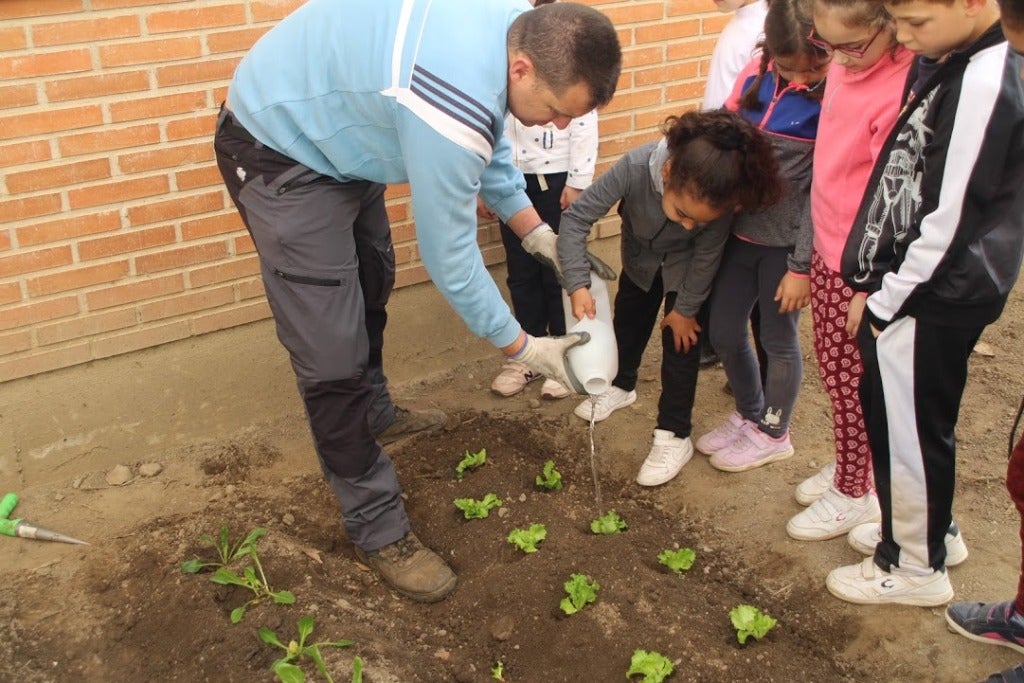 Raúl y varios alumnos regando las plantas. 