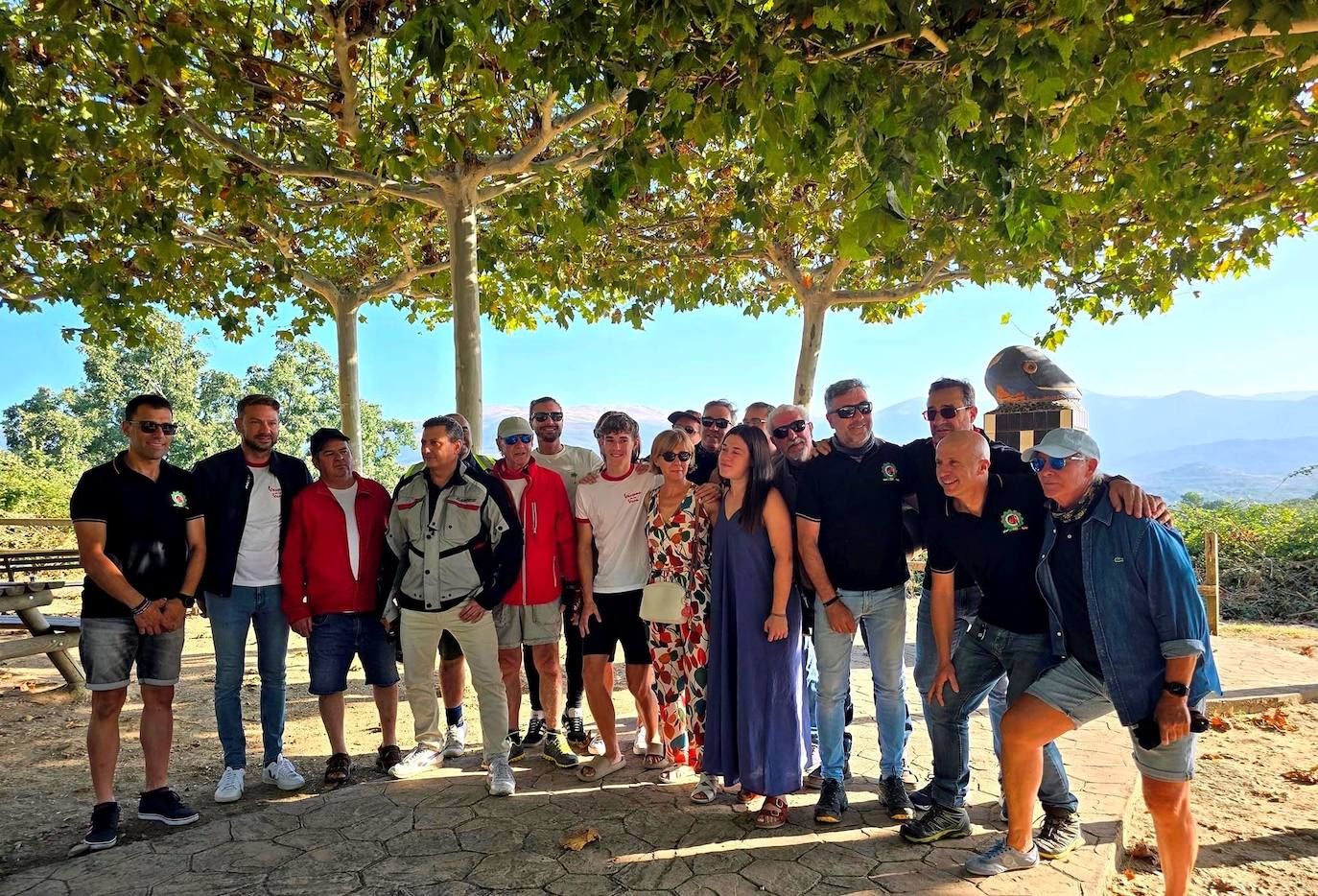 La familia de Víctor Paz arropada por los participantes en la ruta en el monumento dedicado a los moteros.