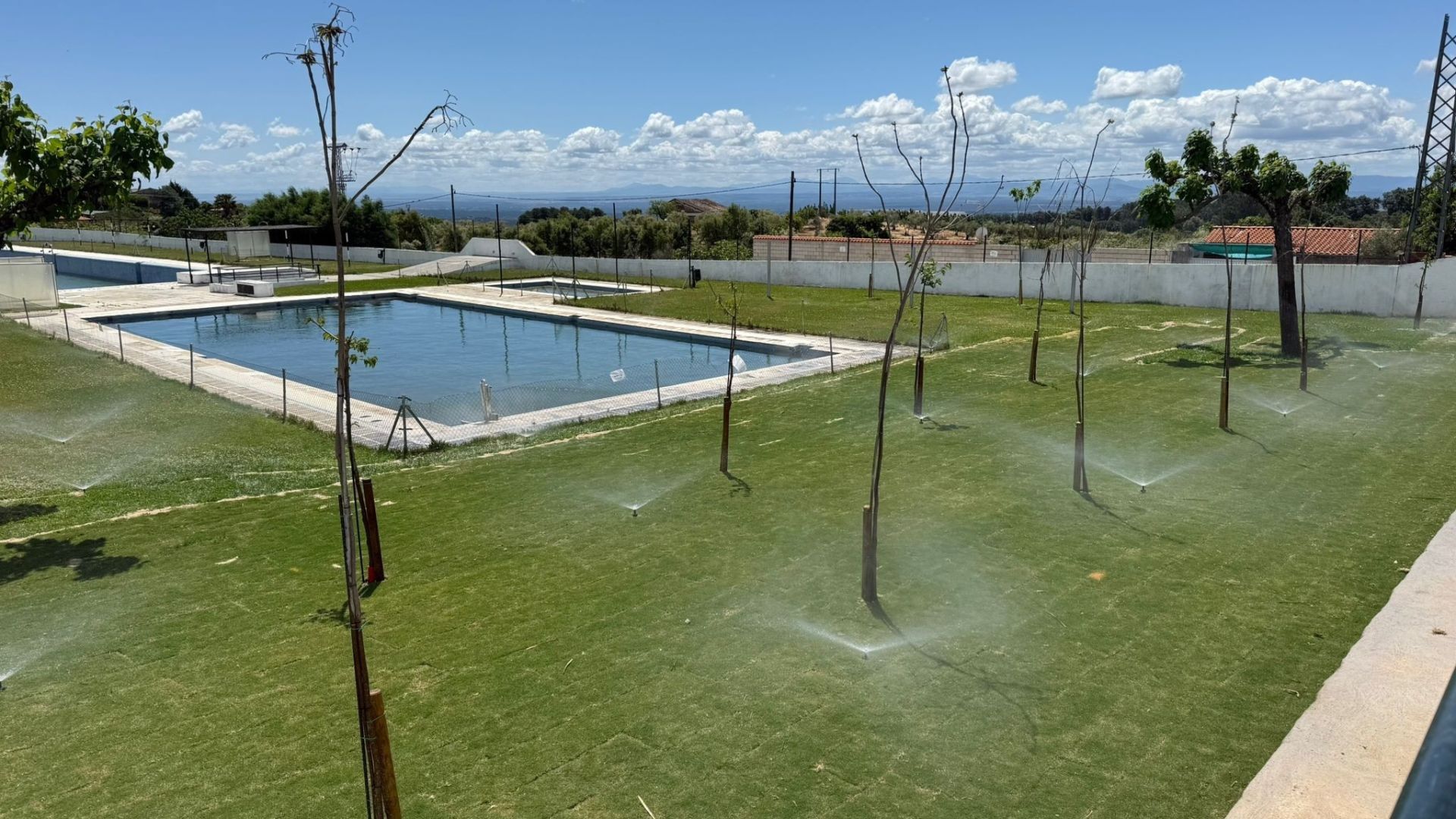 Zona de las piscinas con el nuevo césped y arbolado sustituido.