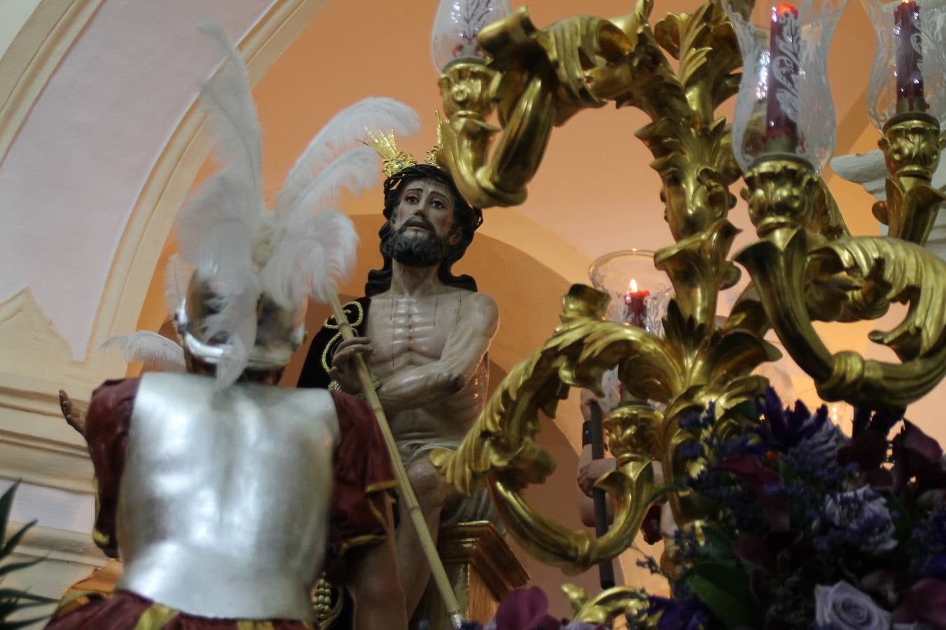 Las emociones llenaron también anoche la ermita de Los Santos Mártires, donde se quedaron guardados todos los afanes, las ilusiones y la devoción que no pudieron tener reflejo en la procesión de las colas largas, La Cofradía del Señor Coronado de Espinas decidió no salir ante la adversidad de la climatología y en el interior de este pequeño templo se vivieron momentos de gran emotividad.La Guardia Civil de Jerez de los Caballeros rindió honores a s Madrina, María Santísima de la Amargura. Los sones de las bandas y agrupaciones que iban a participar en el desfile procesional expandieron su eco desde el Llano de los Mártires para acompañar a los costaleros de cada uno de los tres Pasos, que fueron mecidos a su compás. El jovencísimo saetero Julián Jaramillo, de tan solo 12 años y natural de Segura de León, hizo vibrar a los presentes con su saeta al Coronado.Y entre las oraciones del párroco, Antonio María Rejano y los sacerdotes que le acompañaron, asomaron también las lágrimas.El momento más emotivo se vivió con el sentido homenaje a Manuel Labrador González, Manolo 'Cornelio' a quien Marisa Sánchez, en nombre de la junta de gobierno de la Cofradía del Señor Coronado, dedicó palabras llenas de afecto y reconocimiento, destacando su condición de «trabajador sin igual», su carácter innovador, su generosidad, sus consejos a jóvenes y mayores en el seno de esta Cofradía de la que dijo, «es piedra angular» y su extraordinaria labor. Manuel recibió un libro y una precioso cartel realizada por José Tomás Pérez Indiano, a semejanza del que hace tres años anunció la Semana Santa Jerezana. Emocionado, Manuel agradeció el cariño y dedicó este homenaje a su familia y a todas las madres.