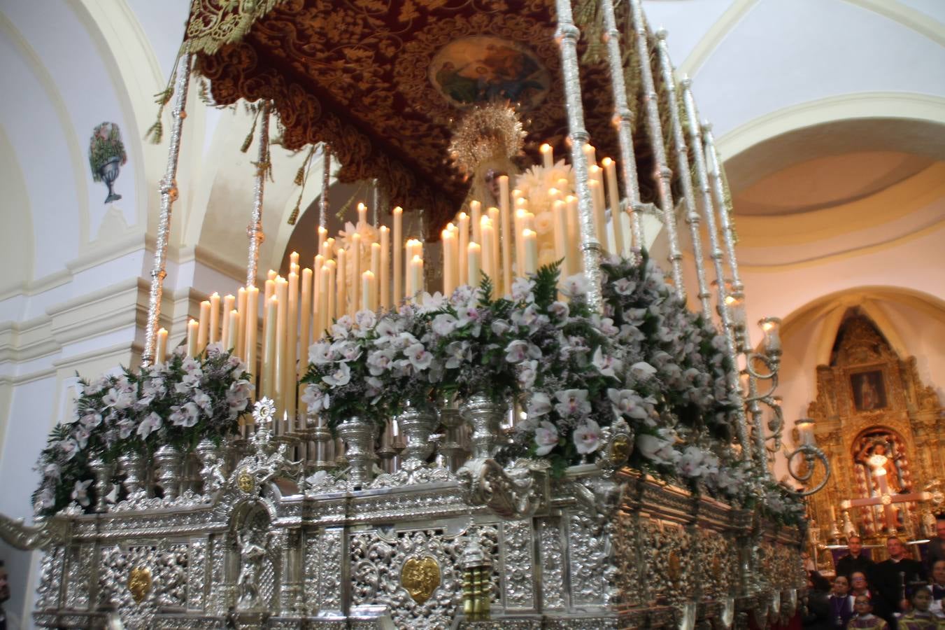 Las emociones llenaron también anoche la ermita de Los Santos Mártires, donde se quedaron guardados todos los afanes, las ilusiones y la devoción que no pudieron tener reflejo en la procesión de las colas largas, La Cofradía del Señor Coronado de Espinas decidió no salir ante la adversidad de la climatología y en el interior de este pequeño templo se vivieron momentos de gran emotividad.La Guardia Civil de Jerez de los Caballeros rindió honores a s Madrina, María Santísima de la Amargura. Los sones de las bandas y agrupaciones que iban a participar en el desfile procesional expandieron su eco desde el Llano de los Mártires para acompañar a los costaleros de cada uno de los tres Pasos, que fueron mecidos a su compás. El jovencísimo saetero Julián Jaramillo, de tan solo 12 años y natural de Segura de León, hizo vibrar a los presentes con su saeta al Coronado.Y entre las oraciones del párroco, Antonio María Rejano y los sacerdotes que le acompañaron, asomaron también las lágrimas.El momento más emotivo se vivió con el sentido homenaje a Manuel Labrador González, Manolo 'Cornelio' a quien Marisa Sánchez, en nombre de la junta de gobierno de la Cofradía del Señor Coronado, dedicó palabras llenas de afecto y reconocimiento, destacando su condición de «trabajador sin igual», su carácter innovador, su generosidad, sus consejos a jóvenes y mayores en el seno de esta Cofradía de la que dijo, «es piedra angular» y su extraordinaria labor. Manuel recibió un libro y una precioso cartel realizada por José Tomás Pérez Indiano, a semejanza del que hace tres años anunció la Semana Santa Jerezana. Emocionado, Manuel agradeció el cariño y dedicó este homenaje a su familia y a todas las madres.
