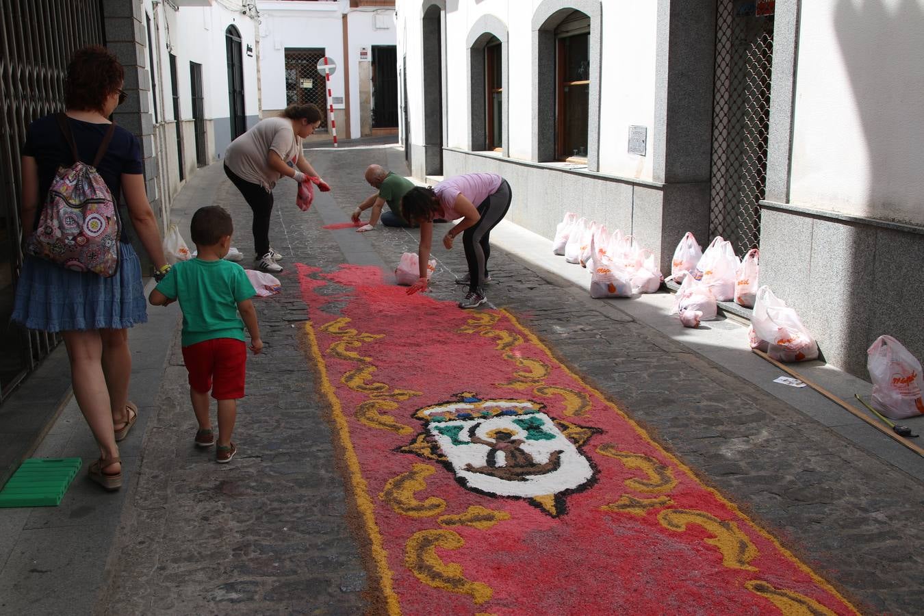 Las alfombras de sal embellecen y llenan de color, hoy, las calles de Jerez de los Caballeros con motivo de la festividad del Corpus Christi. Desde primera hora de la mañana, miembros de las cofradías y hermandades, Cáritas, grupos de catequesis, familias de los niños que han hecho este año la Primera Comunión, miembros de la Asociación de costaleros y costaleras de la Semana Santa jerezana, Ayuntamiento y vecinos han cubierto las principales calles del municipio con 6.250 kilos de sal teñida, plenas de color. A continuación, han disfrutado de una jornada de convivencia en la Casa de la Iglesia 'Cecilia de Arteaga'.