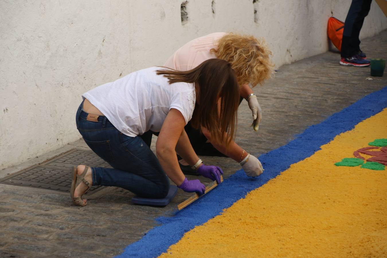 Las alfombras de sal embellecen y llenan de color, hoy, las calles de Jerez de los Caballeros con motivo de la festividad del Corpus Christi. Desde primera hora de la mañana, miembros de las cofradías y hermandades, Cáritas, grupos de catequesis, familias de los niños que han hecho este año la Primera Comunión, miembros de la Asociación de costaleros y costaleras de la Semana Santa jerezana, Ayuntamiento y vecinos han cubierto las principales calles del municipio con 6.250 kilos de sal teñida, plenas de color. A continuación, han disfrutado de una jornada de convivencia en la Casa de la Iglesia 'Cecilia de Arteaga'.
