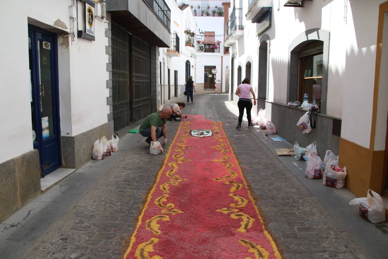 Las alfombras de sal embellecen y llenan de color, hoy, las calles de Jerez de los Caballeros con motivo de la festividad del Corpus Christi. Desde primera hora de la mañana, miembros de las cofradías y hermandades, Cáritas, grupos de catequesis, familias de los niños que han hecho este año la Primera Comunión, miembros de la Asociación de costaleros y costaleras de la Semana Santa jerezana, Ayuntamiento y vecinos han cubierto las principales calles del municipio con 6.250 kilos de sal teñida, plenas de color. A continuación, han disfrutado de una jornada de convivencia en la Casa de la Iglesia 'Cecilia de Arteaga'.