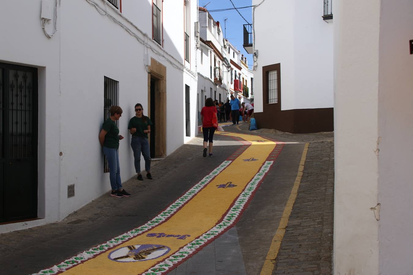 Las alfombras de sal embellecen y llenan de color, hoy, las calles de Jerez de los Caballeros con motivo de la festividad del Corpus Christi. Desde primera hora de la mañana, miembros de las cofradías y hermandades, Cáritas, grupos de catequesis, familias de los niños que han hecho este año la Primera Comunión, miembros de la Asociación de costaleros y costaleras de la Semana Santa jerezana, Ayuntamiento y vecinos han cubierto las principales calles del municipio con 6.250 kilos de sal teñida, plenas de color. A continuación, han disfrutado de una jornada de convivencia en la Casa de la Iglesia 'Cecilia de Arteaga'.