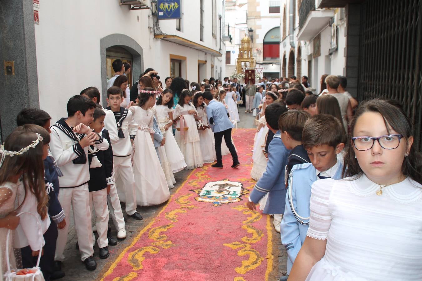 Jerez de los Caballeros celebró ayer la festividad del Corpus Christi en medio de un ambiente de solemnidad y convivencia del que fueron partícipes cientos de personas.La iglesia visigoda de Santa María de la Encarnación, llena de fieles, acogió la celebración de la Eucaristía que dió paso a la procesión acompañando la Santa Custodia en el magnífico templete de la iglesia de San Miguel, sobre las andas de la Virgen de Aguasantas y portada por costaleros y costaleras de la recién Asociación creada en esta ciudad. El párroco, Antonio María Rejano, destacó la significación de esta procesión, lamás grande, dijo, «porque Jesús sale a nuestras vidas, a nuestro encuentro y nosotros le acompañamos». Al término de la misa, incidió en el agradecimiento a todas las personas que han participado para hacer posible su desarrollo, trabajando desde la jornada del sábado en la elaboración de las preciosas alfombras de sal teñida de colores, que lucieron en las calles del centro de Jerez. El agradecimiento fue especial para los padres y madres de los niños y niñas que han hecho la Primera Comunión, para éstos mismos, también para catequistas, Cofradías y Hermandades, la Asociación del costaleros y costaleras de la Semana Santa de Jerez de los Caballeros, Ayuntamiento, Policía Local, grupos y personas de la parroquia.Autoridades civiles en representación del Ayuntamiento, Policía Local y Guardia Civil, acompañaron el desarrollo de la procesión junto a representantes de todas las cofradías y hermandades jerezanas y el protagonismo de los más de 80 niños y niñas que este año han celebrado su Primera Comunión.  A lo largo de todo el recorrido se instalaron distintos altares, también con la colaboración de vecinos y centros como la Residencia de Mayores Hernando de Soto. Los magníficos sones de la Agrupación Musical 'Nuestro Padre Jesús Nazareno' coronaron esta hermosa procesión.