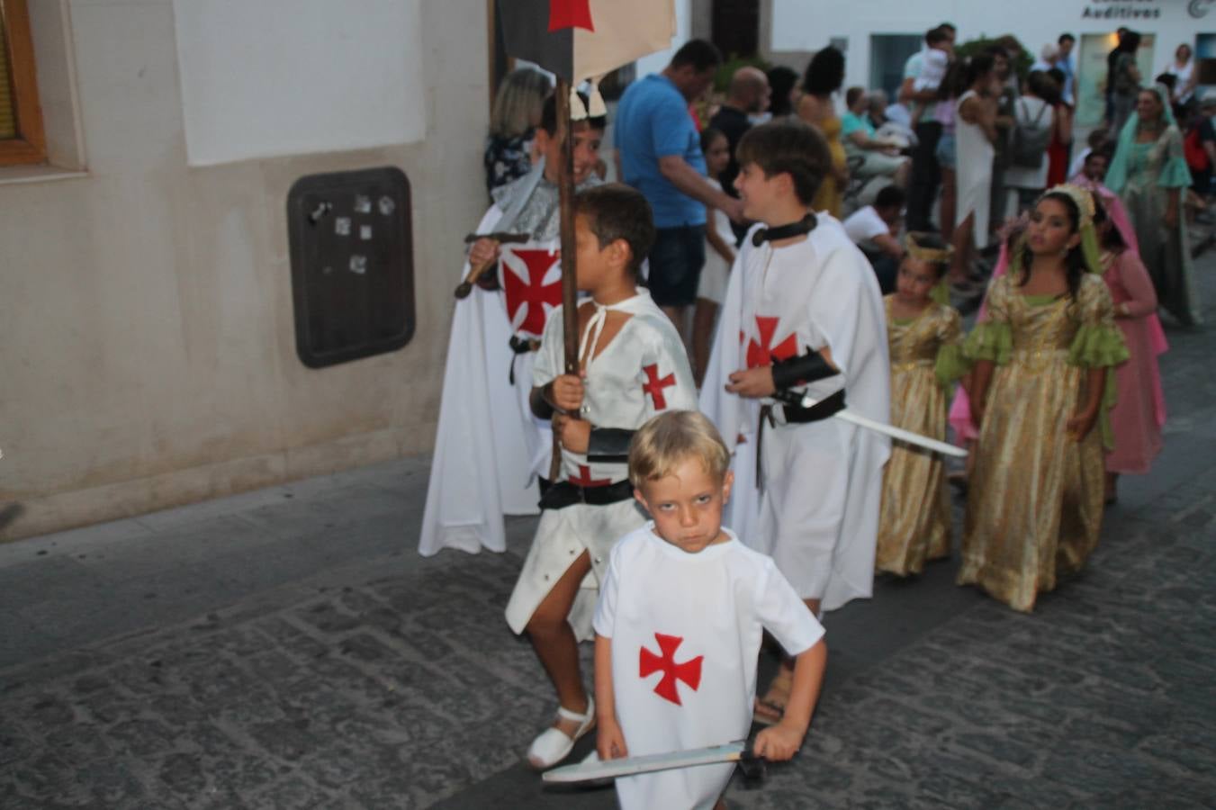La participación popular fue nuevo protagonista del desfile teatralizado que anoche inauguró el grueso de la programación del XVI Festival Templario, invitando a propios y visitantes a revivir un pasado de leyenda, concretamente el siglo en el que La Orden del Temple marcó la vida de esta ciudad, en la que tuvo una de sus principales Encomiendas, siendo además el último reducto de Los Templarios en los reinos de España.La Asociación juvenil y cultural 'La Trouppe' estuvo al frente de la coordinación de dicho desfile que llenó de ambiente y animación las calles y plazas del centro histórico de Jerez de los Caballeros, llenas de público y engalanadas para la ocasión con pendones con la cruz templaria y otros elementos referentes a la cultura árabe que dejó su impronta en aquella época. Destacó la participación de más de 60 niñas que pusieron alegría con sus bailes a este pasacalle, junto a personajes fantásticos en zancos, la melodía de la Asociación Musical de Jerez de los Caballeros y la participación de asociaciones, como la del Belén 'Santa Ángela', Euexia Rural, además de los caballeros del campamento medieval a cargo de Cabalbur y de manera especial, la implicación de numerosos vecinos de todas las edades que desfilaron ataviados con indumentaria de la época dando vida a esta celebración.