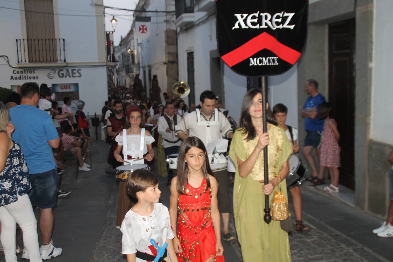 La participación popular fue nuevo protagonista del desfile teatralizado que anoche inauguró el grueso de la programación del XVI Festival Templario, invitando a propios y visitantes a revivir un pasado de leyenda, concretamente el siglo en el que La Orden del Temple marcó la vida de esta ciudad, en la que tuvo una de sus principales Encomiendas, siendo además el último reducto de Los Templarios en los reinos de España.La Asociación juvenil y cultural 'La Trouppe' estuvo al frente de la coordinación de dicho desfile que llenó de ambiente y animación las calles y plazas del centro histórico de Jerez de los Caballeros, llenas de público y engalanadas para la ocasión con pendones con la cruz templaria y otros elementos referentes a la cultura árabe que dejó su impronta en aquella época. Destacó la participación de más de 60 niñas que pusieron alegría con sus bailes a este pasacalle, junto a personajes fantásticos en zancos, la melodía de la Asociación Musical de Jerez de los Caballeros y la participación de asociaciones, como la del Belén 'Santa Ángela', Euexia Rural, además de los caballeros del campamento medieval a cargo de Cabalbur y de manera especial, la implicación de numerosos vecinos de todas las edades que desfilaron ataviados con indumentaria de la época dando vida a esta celebración.