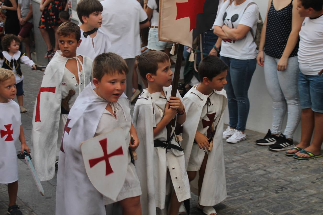 La participación popular fue nuevo protagonista del desfile teatralizado que anoche inauguró el grueso de la programación del XVI Festival Templario, invitando a propios y visitantes a revivir un pasado de leyenda, concretamente el siglo en el que La Orden del Temple marcó la vida de esta ciudad, en la que tuvo una de sus principales Encomiendas, siendo además el último reducto de Los Templarios en los reinos de España.La Asociación juvenil y cultural 'La Trouppe' estuvo al frente de la coordinación de dicho desfile que llenó de ambiente y animación las calles y plazas del centro histórico de Jerez de los Caballeros, llenas de público y engalanadas para la ocasión con pendones con la cruz templaria y otros elementos referentes a la cultura árabe que dejó su impronta en aquella época. Destacó la participación de más de 60 niñas que pusieron alegría con sus bailes a este pasacalle, junto a personajes fantásticos en zancos, la melodía de la Asociación Musical de Jerez de los Caballeros y la participación de asociaciones, como la del Belén 'Santa Ángela', Euexia Rural, además de los caballeros del campamento medieval a cargo de Cabalbur y de manera especial, la implicación de numerosos vecinos de todas las edades que desfilaron ataviados con indumentaria de la época dando vida a esta celebración.