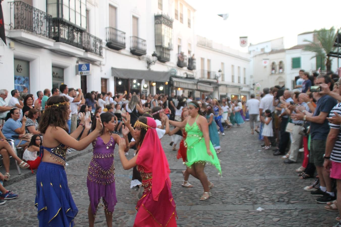 La participación popular fue nuevo protagonista del desfile teatralizado que anoche inauguró el grueso de la programación del XVI Festival Templario, invitando a propios y visitantes a revivir un pasado de leyenda, concretamente el siglo en el que La Orden del Temple marcó la vida de esta ciudad, en la que tuvo una de sus principales Encomiendas, siendo además el último reducto de Los Templarios en los reinos de España.La Asociación juvenil y cultural 'La Trouppe' estuvo al frente de la coordinación de dicho desfile que llenó de ambiente y animación las calles y plazas del centro histórico de Jerez de los Caballeros, llenas de público y engalanadas para la ocasión con pendones con la cruz templaria y otros elementos referentes a la cultura árabe que dejó su impronta en aquella época. Destacó la participación de más de 60 niñas que pusieron alegría con sus bailes a este pasacalle, junto a personajes fantásticos en zancos, la melodía de la Asociación Musical de Jerez de los Caballeros y la participación de asociaciones, como la del Belén 'Santa Ángela', Euexia Rural, además de los caballeros del campamento medieval a cargo de Cabalbur y de manera especial, la implicación de numerosos vecinos de todas las edades que desfilaron ataviados con indumentaria de la época dando vida a esta celebración.