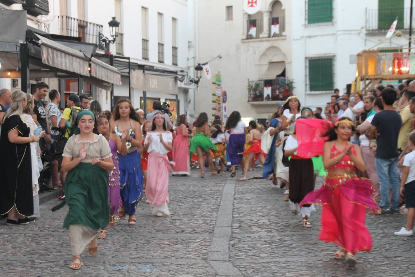 La participación popular fue nuevo protagonista del desfile teatralizado que anoche inauguró el grueso de la programación del XVI Festival Templario, invitando a propios y visitantes a revivir un pasado de leyenda, concretamente el siglo en el que La Orden del Temple marcó la vida de esta ciudad, en la que tuvo una de sus principales Encomiendas, siendo además el último reducto de Los Templarios en los reinos de España.La Asociación juvenil y cultural 'La Trouppe' estuvo al frente de la coordinación de dicho desfile que llenó de ambiente y animación las calles y plazas del centro histórico de Jerez de los Caballeros, llenas de público y engalanadas para la ocasión con pendones con la cruz templaria y otros elementos referentes a la cultura árabe que dejó su impronta en aquella época. Destacó la participación de más de 60 niñas que pusieron alegría con sus bailes a este pasacalle, junto a personajes fantásticos en zancos, la melodía de la Asociación Musical de Jerez de los Caballeros y la participación de asociaciones, como la del Belén 'Santa Ángela', Euexia Rural, además de los caballeros del campamento medieval a cargo de Cabalbur y de manera especial, la implicación de numerosos vecinos de todas las edades que desfilaron ataviados con indumentaria de la época dando vida a esta celebración.