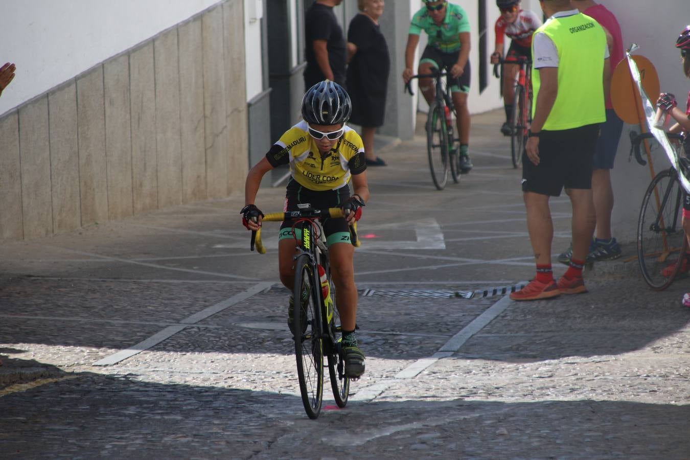 El barrio de 'Santa Catalina' de Jerez de los Caballeros ha acogido, esta mañana, la tercera prueba del Gran Premio Diputación de Badajoz 'Copa Escuelas de ciclismo en carretera', organizada por el Club Ciclista Jerez de los Caballeros y la Federación Extremeña de Ciclismo.Una competición de ciclismo que, como ya adelantó HOY Jerez, fue creada por la Federación Extremeña de Ciclismo con el objetivo de fomentar y seguir practicando deporte cuando ya han terminado todos los circuitos que se celebran durante el curso académico. En la citada prueba, han participado diferentes categorías: cadete, promesa, junior, principiante, alevín e infantil.Juan Luis Soriano, presidente del Club Ciclista Jerez, ha manifestado su satisfacción por el buen desarrollo de la jornada, «este tipo de pruebas son fundamentales para hacer cantera y promover este deporte entre los más pequeños».