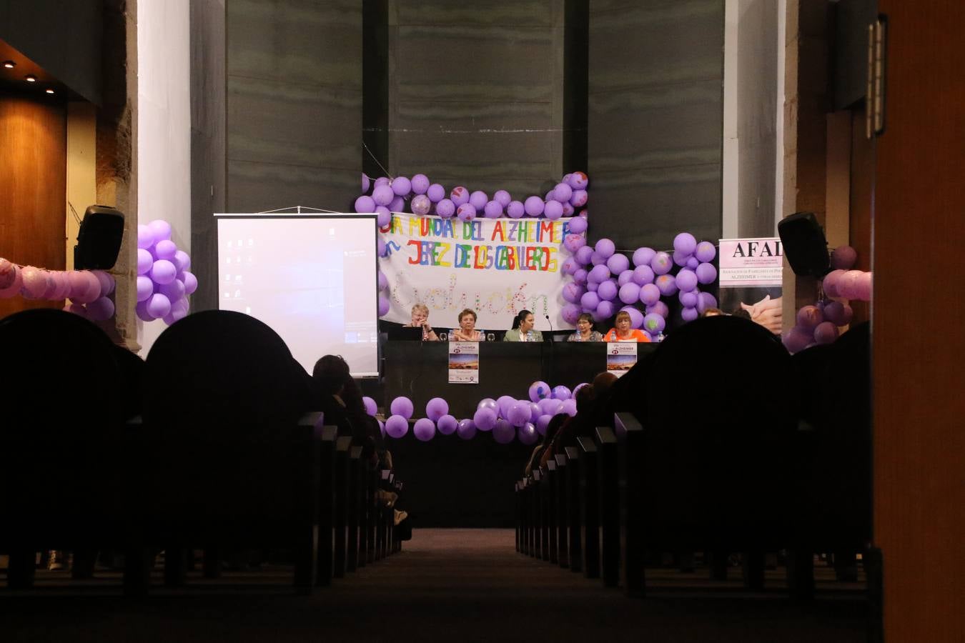 Ante las condiciones climatológicas adversas, el auditorio del Conventual San Agustín se convirtió en el mejor escenario para acoger las actividades que, con motivo del Día Mundial del Alzhéimer, la Asociación de Familiares de Personas con Alzheimer y otras Demencias de Jerez de los Caballeros y Comarca Sierra Suroeste (AFAD) había preparado en el municipio. Una gran pancarta con el lema 'Evolución', realizada por los alumnos del Colegio de Educación Especial 'Nuestra Señora de Aguasantas', presidió el escenario, y una marea de globos morados con distintos dibujos, realizados por los alumnos de los colegios 'Sotomayor y Terrazas' y 'El Rodeo', tiñó de color, empatía, sensibilidad y creatividad el citado auditorio.La jornada comenzó con la canción 'Estoy contigo' de la Oreja de Van Gogh. A continuación, tuvo lugar una mesa redonda en la que cinco personas contaron su testimonio en relación a esta enfermedad. Posteriormente, se dio paso a la lectura de un manifiesto; la entrega de diploma a las personas y colectivos colaboradores, y la lectura de dos cuentos infantiles.