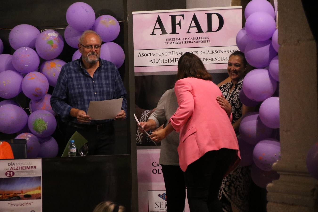 Ante las condiciones climatológicas adversas, el auditorio del Conventual San Agustín se convirtió en el mejor escenario para acoger las actividades que, con motivo del Día Mundial del Alzhéimer, la Asociación de Familiares de Personas con Alzheimer y otras Demencias de Jerez de los Caballeros y Comarca Sierra Suroeste (AFAD) había preparado en el municipio. Una gran pancarta con el lema 'Evolución', realizada por los alumnos del Colegio de Educación Especial 'Nuestra Señora de Aguasantas', presidió el escenario, y una marea de globos morados con distintos dibujos, realizados por los alumnos de los colegios 'Sotomayor y Terrazas' y 'El Rodeo', tiñó de color, empatía, sensibilidad y creatividad el citado auditorio.La jornada comenzó con la canción 'Estoy contigo' de la Oreja de Van Gogh. A continuación, tuvo lugar una mesa redonda en la que cinco personas contaron su testimonio en relación a esta enfermedad. Posteriormente, se dio paso a la lectura de un manifiesto; la entrega de diploma a las personas y colectivos colaboradores, y la lectura de dos cuentos infantiles.