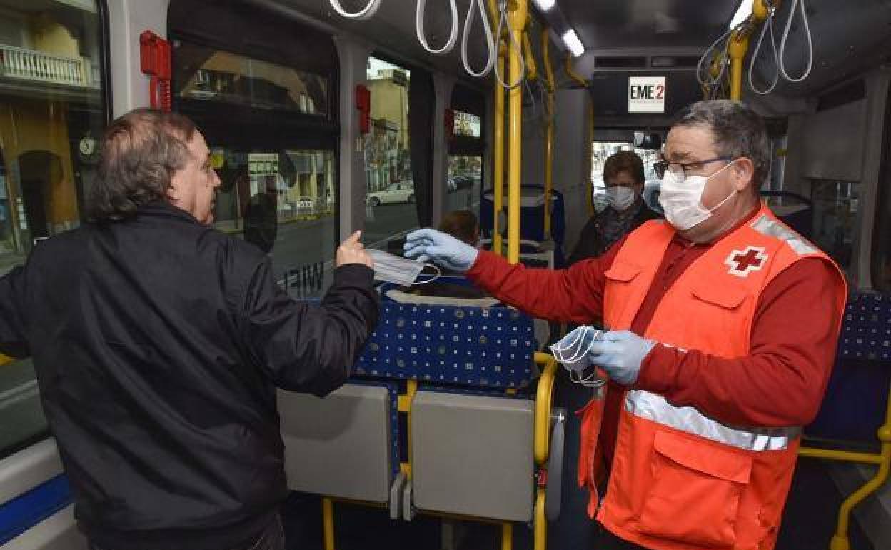 Un voluntario de Cruz Roja entrega una mascarilla en un autobús urbano de Badajoz esta semana. 