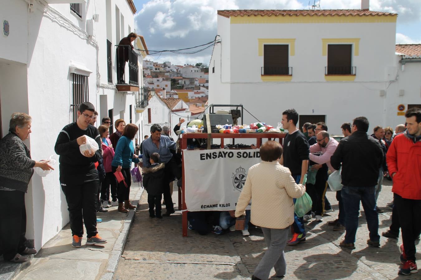 Veciinos depositando alimentos no perecederos sobre las andas durante el ensayo solidario.