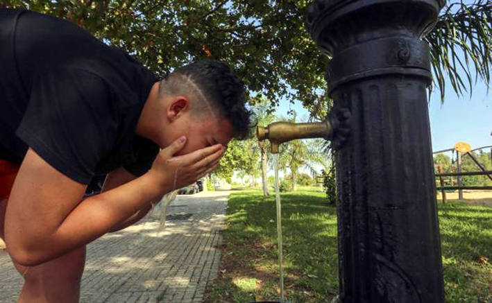 Un joven alivia el calor en una fuente