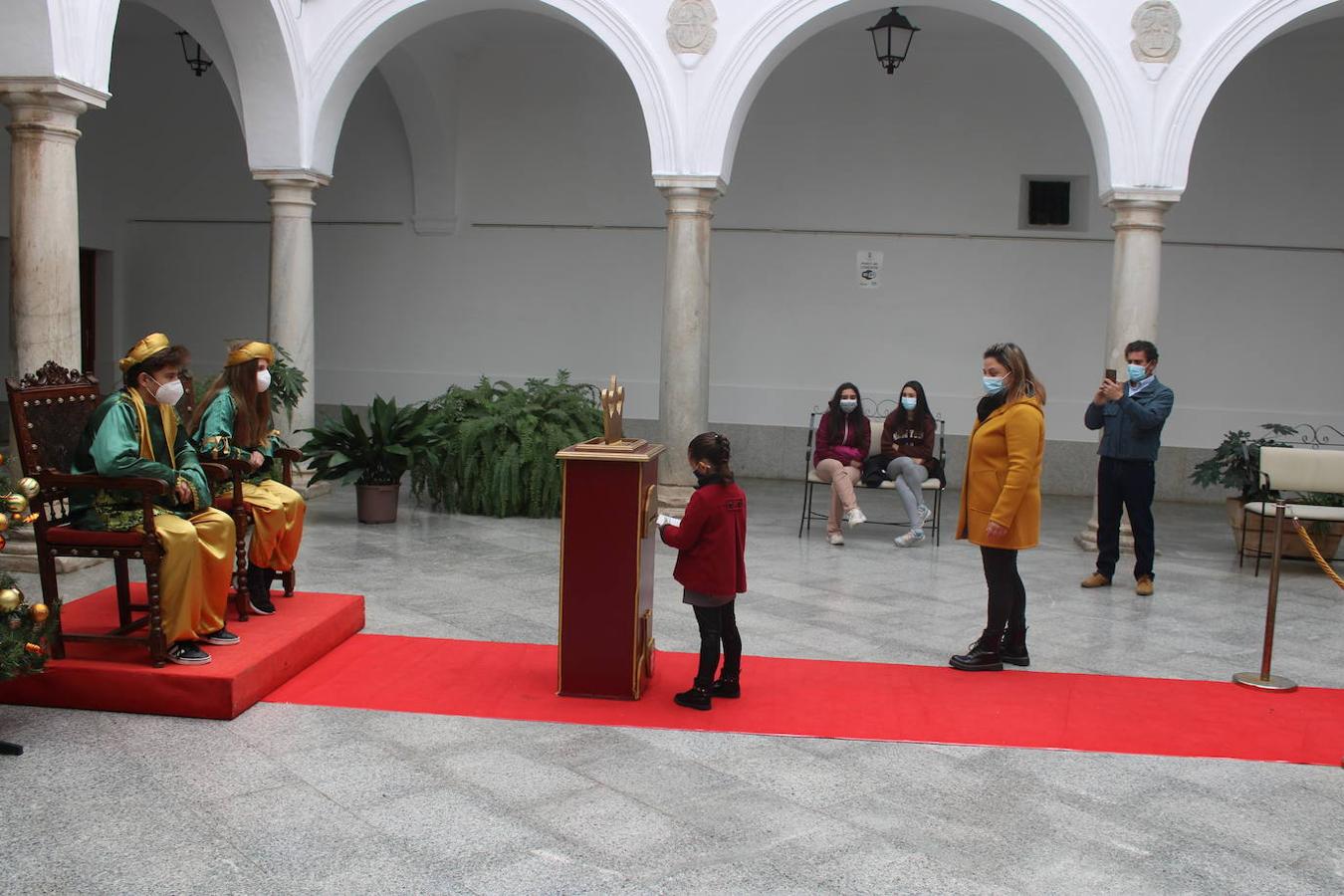Una niña introduce su carta a los Reyes Magos en el buzón.