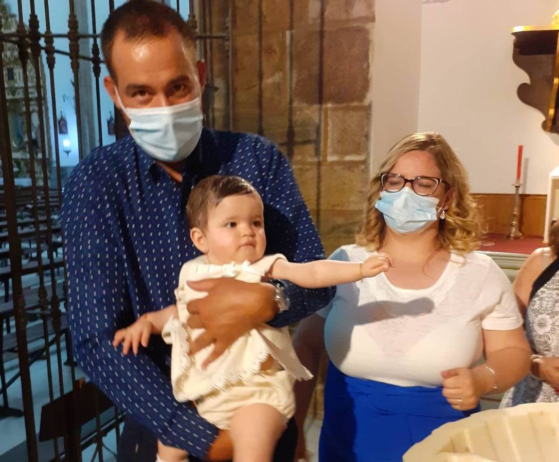 Los padres con su hija ya bautizada junto a la pila 