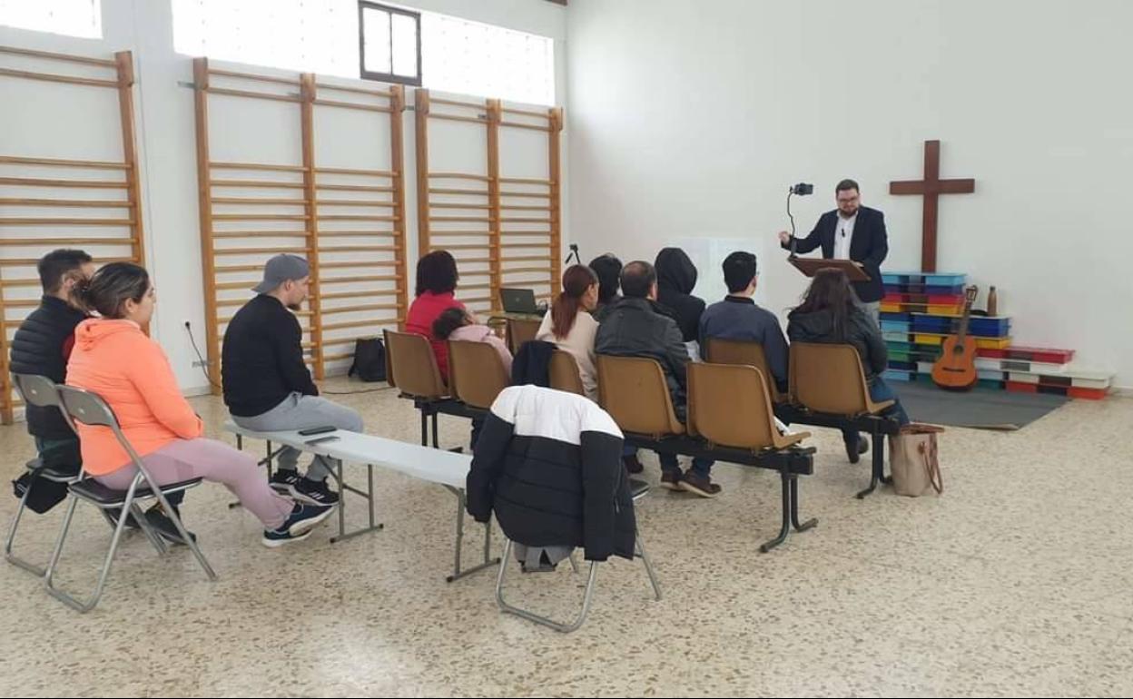 En un rincón del gimnasio, el pastor Samuel y sus feligreses 