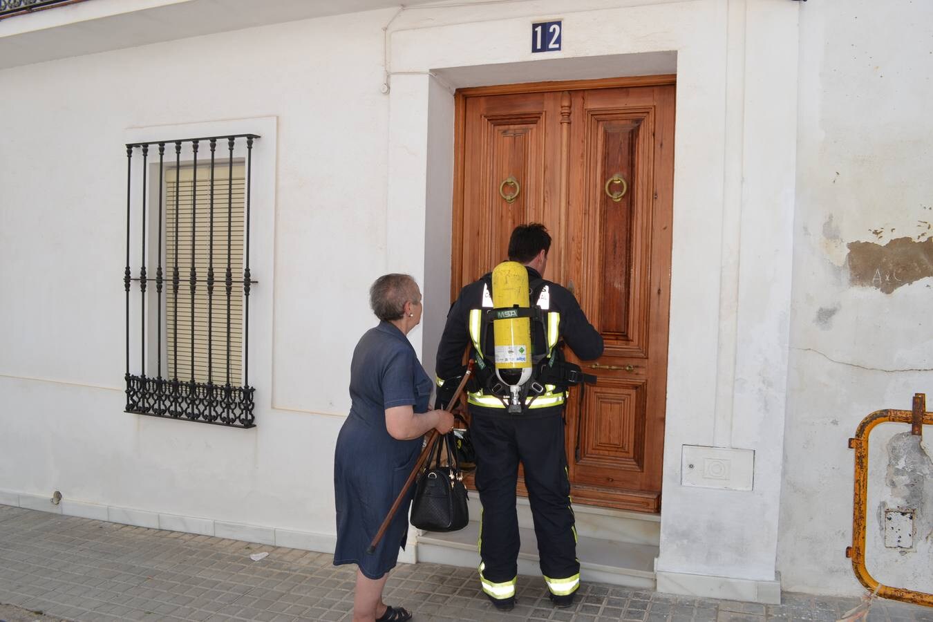Un bombero abre la puerta acompañado de la vecina de la casa en la calle El Pozo.