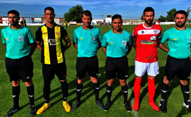 Los capitanes de ambos equipos posan junto al equipo arbitral 