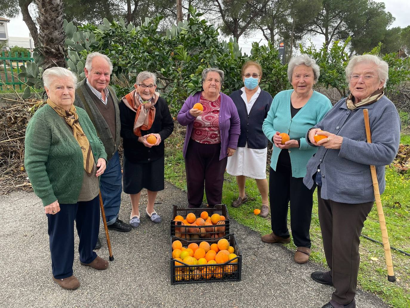 Los mayores posan con las naranjas recolectadas 