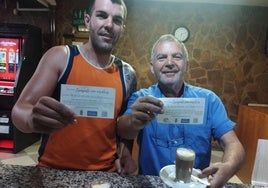 Los clientes de un bar posan con sus papeletas tras pedir un café.