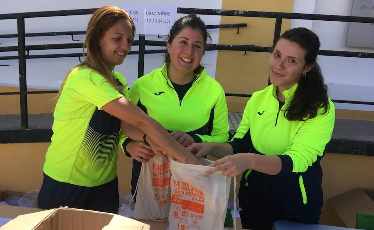 Tres alumnas de Aguablanca I preparan las mochilas que llevarán los participantes en la carrera, este domingo