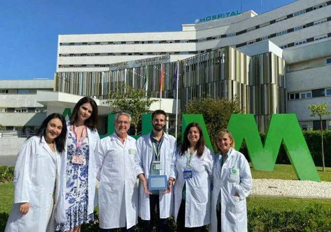 Manuel Delgado sostiene el premio junto a sus compañeros a las puertas del Hospital Virgen Macarena de Sevilla