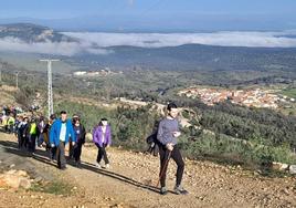 Participantes en la ruta en plena subida con Casas de Miravete al fondo