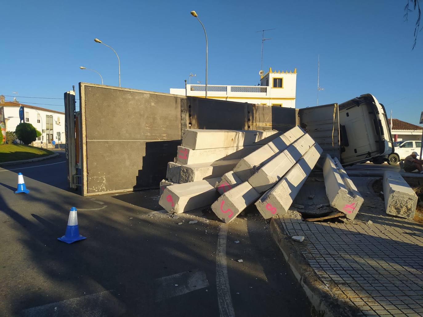Imagen secundaria 1 - Arriba, un agente de la Policía Local de Olivenza, regula el tráfico en la intersección. Abajo, camión volcado y vigas de hormigón que transportaba. 
