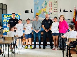 Los escolares muestran sus diplomas junto a los agentes y el regidor local.
