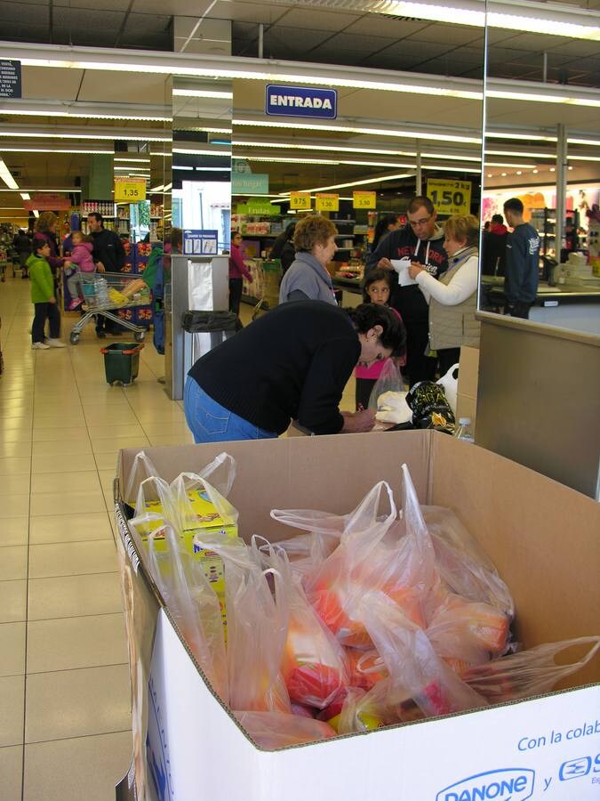 Voluntariado del Banco de Alimentos explica, junto a una caja de recogida, el objetivo de la acción. 