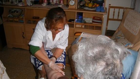 Una técnico de Ayuda a Domicilio atiende a una persona mayor en su hogar. 