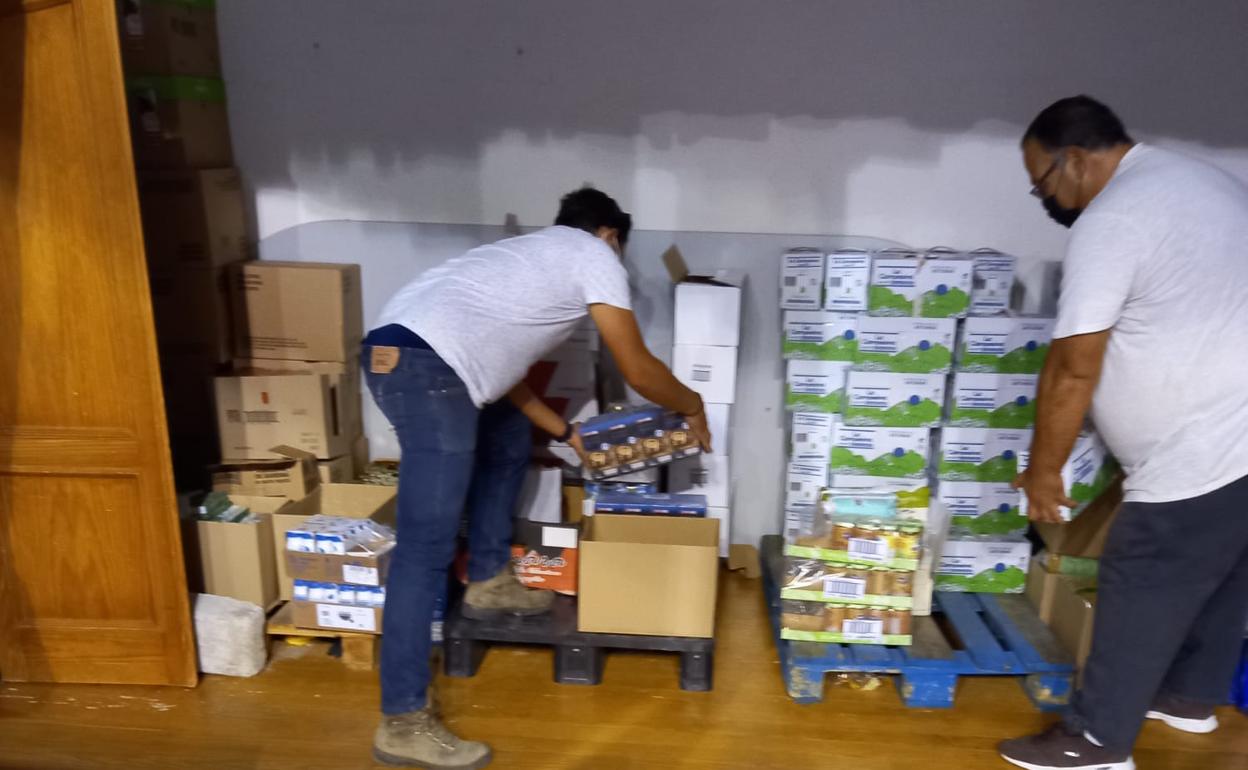 Dos voluntarios de la asociación colocan los palés de alimentos 