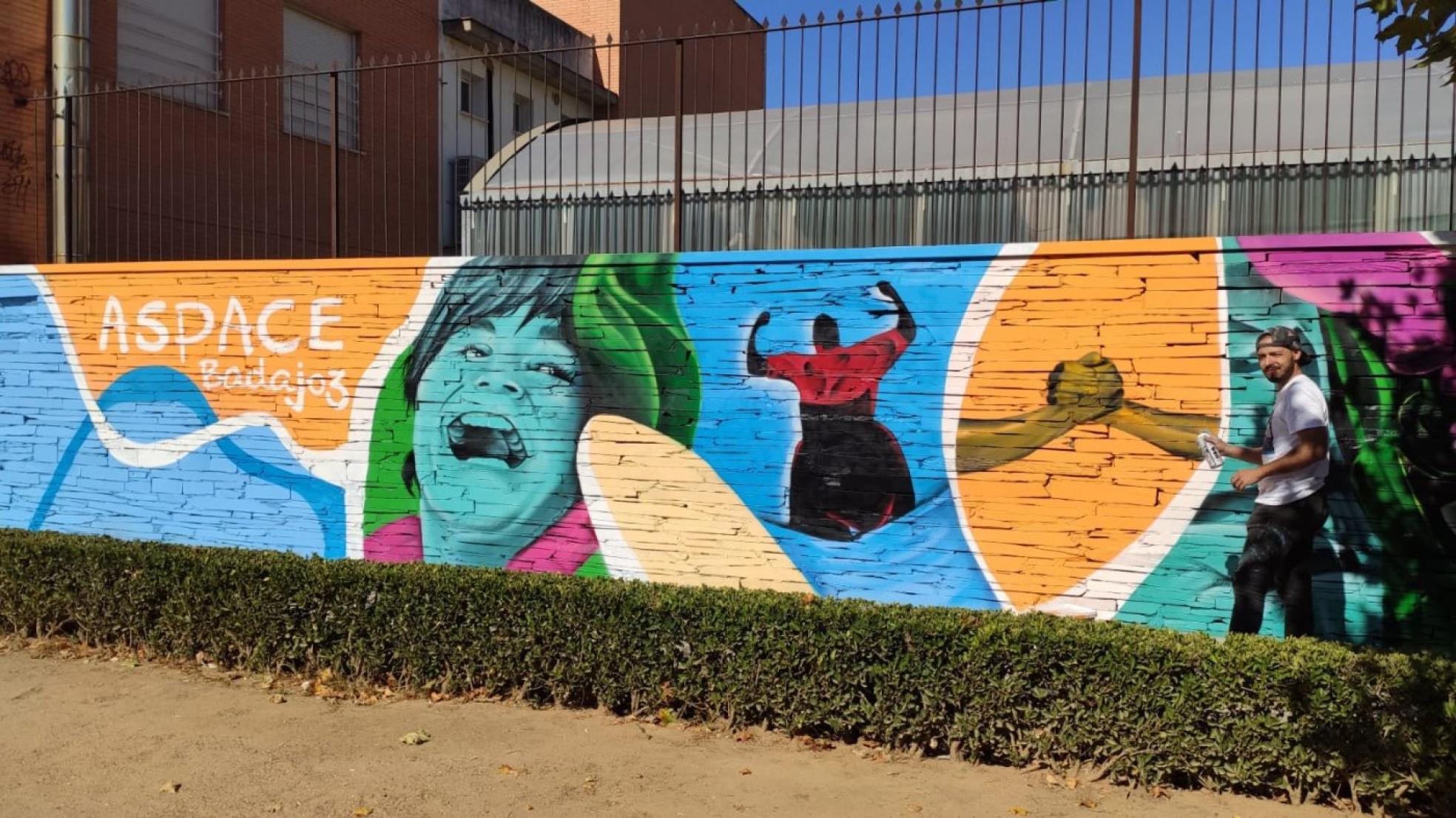 Alejandro Pajuelo 'Chino' posa junto al mural que ha creado en la sede de Aspace Badajoz. 