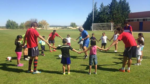 Niños del Espacio Educativo Saludable de Almendralejo jugando con la plantilla del equipo de fútbol Extremadura U. D.