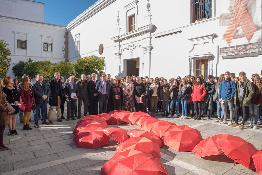 Representantes políticos, con Blanca Martín en el centro, y alumnos del instituto Santa Eulalia de Mérida, en torno a un gran lazo rojo en el Día Mundial de la Lucha contra el Sida.