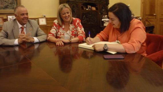 La consejera de Agricultura, Begoña García, firma en el lLbro de Honores del Ayuntamiento, en presencia de la presidenta de la Asamblea de Extremadura, Blanca Martín. 