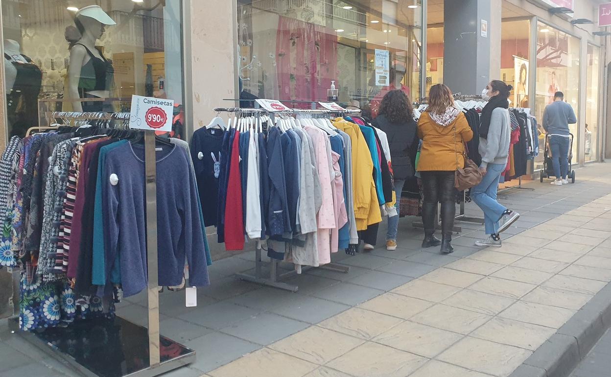 Clientes visitan las tiendas con sus artículos en la calle. 