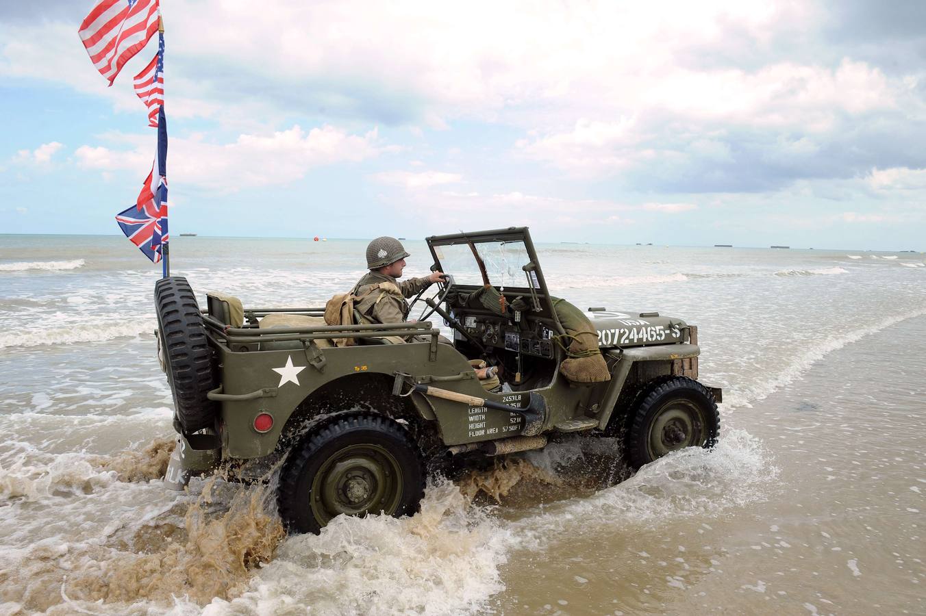 Un hombre francés vestido con ropa militar de época conduce un viejo jeep militar americano en la playa en Arromanches-les-Bains. AFP PHOTO / JEAN FRANCOIS MONIER