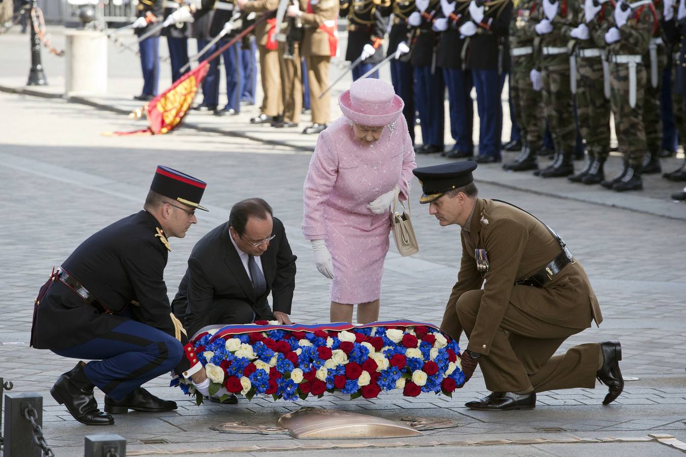 El presidente francés, Francois Hollande (2 ª Iz.) y la reina Isabel II de Inglaterra (2 ª Dcha.) coloca una ofrenda floral en la Tumba del Soldado Desconocido en el Arco del Triunfo en París. AFP PHOTO / POOL / JACQUES BRINON