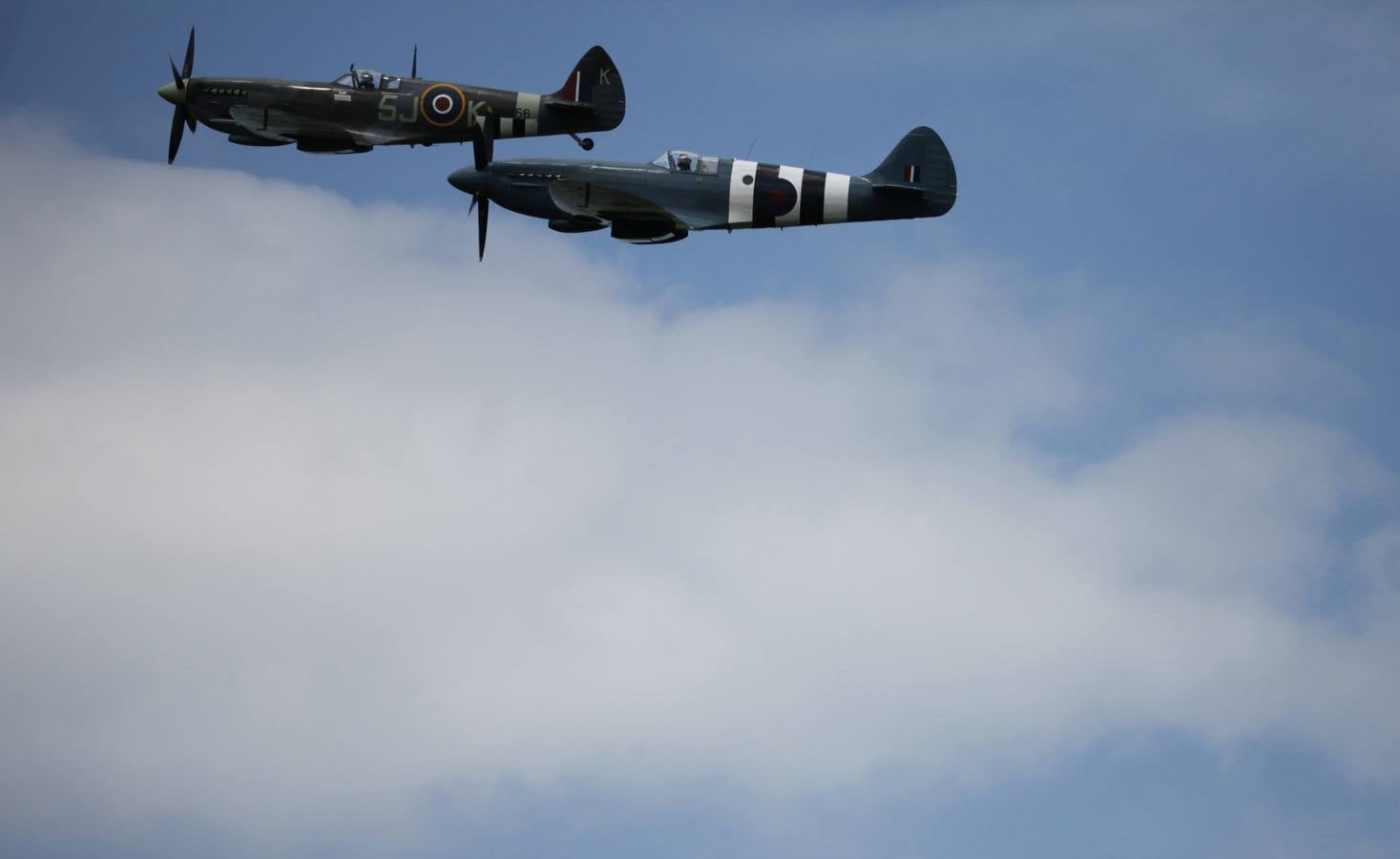 Un par de soldados de la Real Fuerza Aérea Spitfire realiza una pasada sobre los asistentes a la exhibición del día D en la que han participado 300 paracaidistas de diferentes nacionalidades, en Ranville, Francia . REUTERS / Chris Helgren.