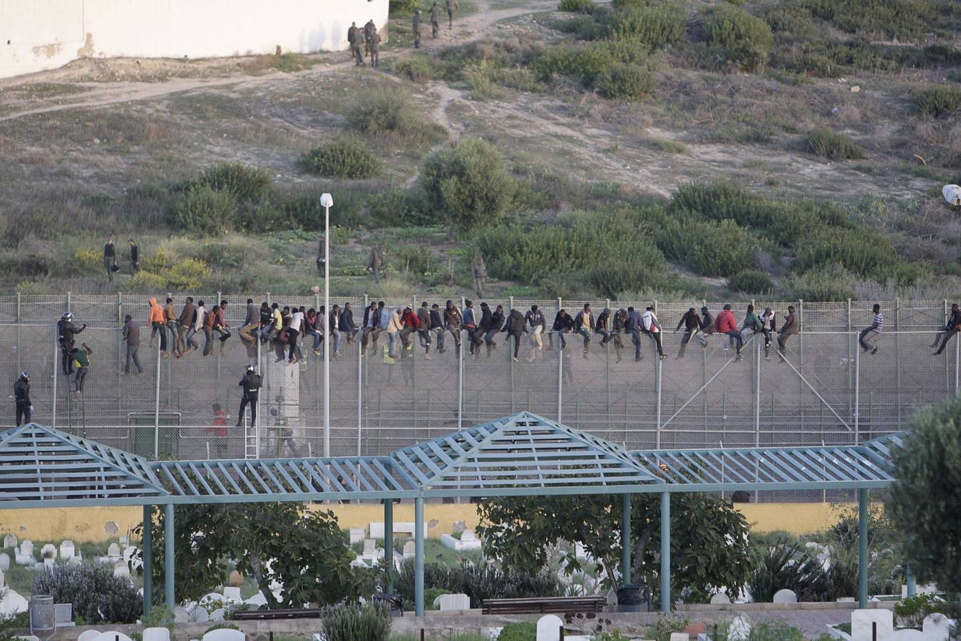 Decenas de inmigrantes encaramados en la valla fronteriza de Melilla