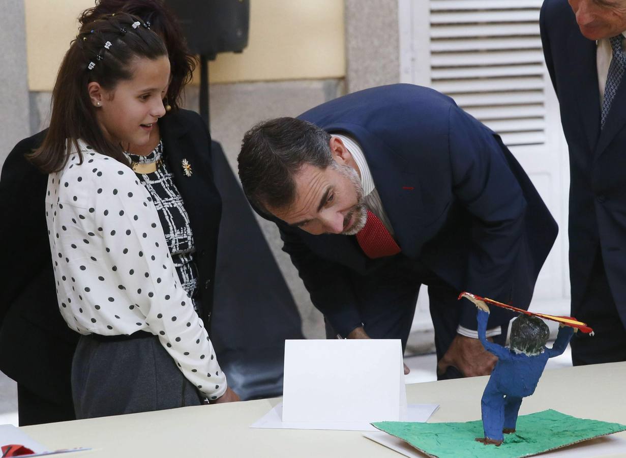 El rey Felipe VI observa el trabajo de una de las niñas ganadoras de la XXXII y XXXIII edición del concurso escolar '¿Qué es un rey para ti?'.