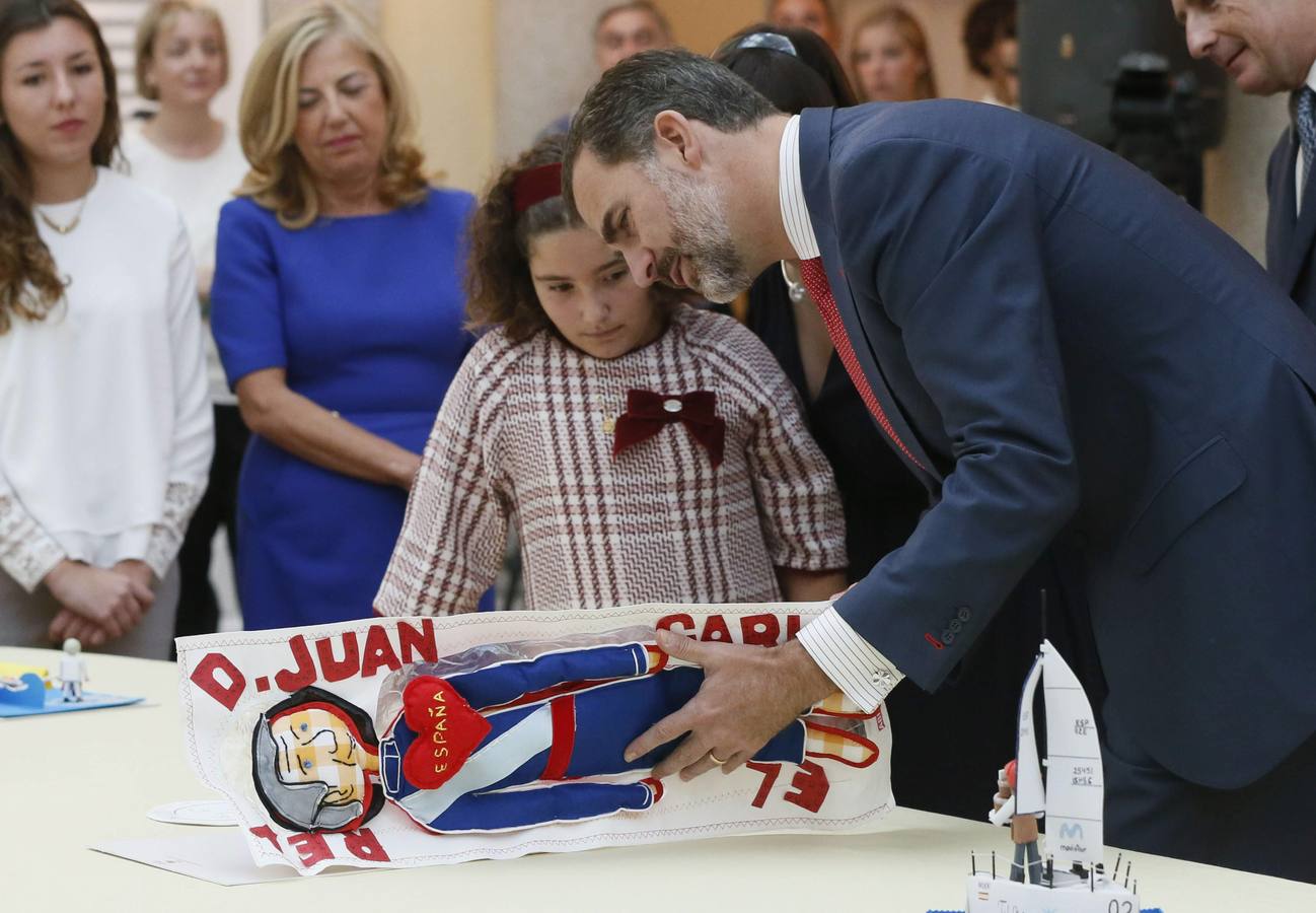 El rey Felipe VI observa el trabajo de una de las niñas ganadoras de la XXXII y XXXIII ediciónes del concurso escolar '¿Qué es un Rey para ti?'.